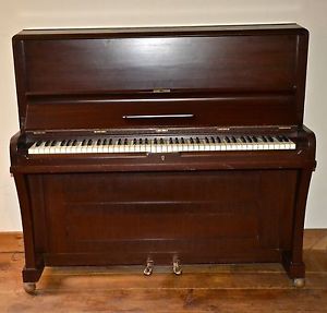 Upright piano by Gilbert London, on rollers, all keys work